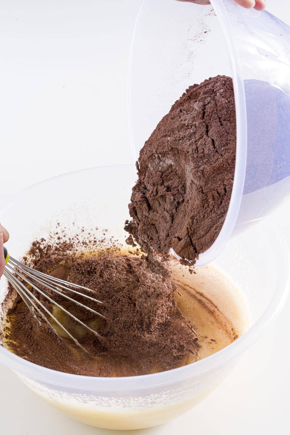 chef adicionando cacau em pó em outro bowl que ja contem outros ingredientes enquanto ele bate com um fouet