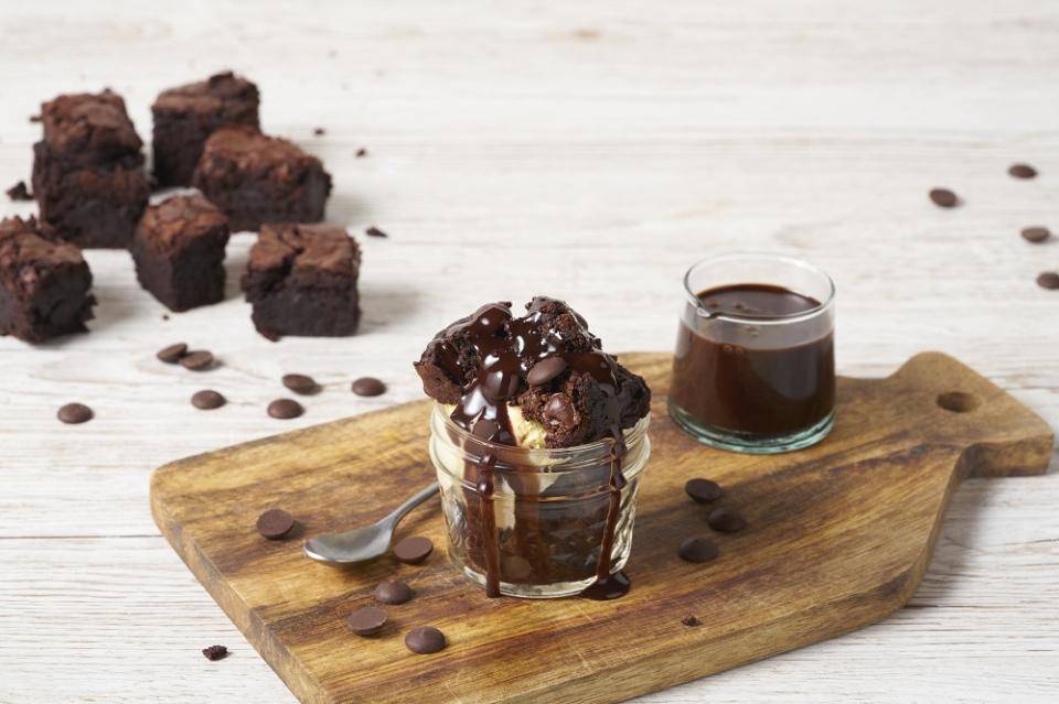 A woman holds a plate of tall, decadent layered brownies