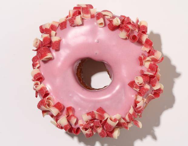 donut dipped in pink ganache, rimmed with pink and white curls